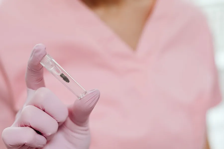 Dental professional holding a titanium implant post — the same Straumann system used at Taki Dent Antalya