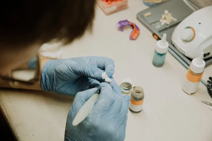Dental laboratory technician hand-crafting a precision ceramic restoration at Taki Dent Antalya — in-house lab quality control ensures every crown and veneer meets the highest standards