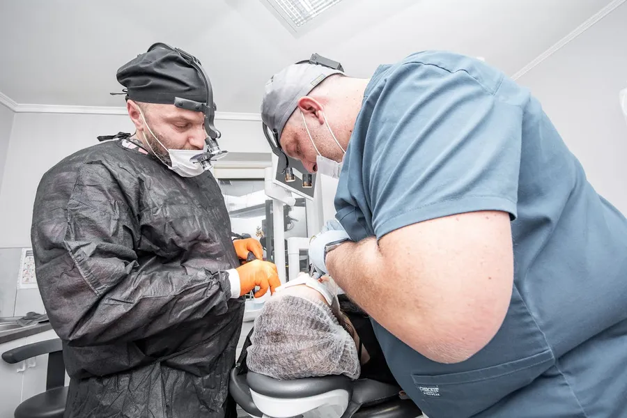 Two dental surgery professionals in surgical scrubs at Taki Dent Antalya — the specialist implantology team led by Dr. Barış Kıprıtoglu, ITI Fellow